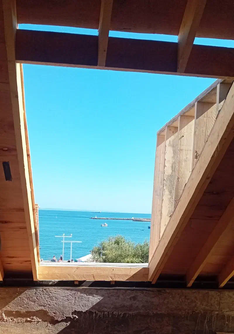 The new mezzanine timber structure framing the sea view from the Cascais apartment
